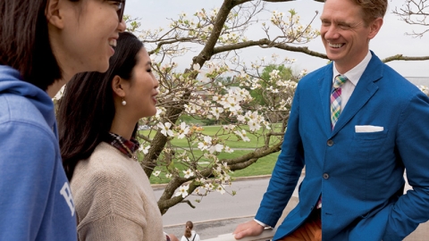 Two students chat with a Communications professor