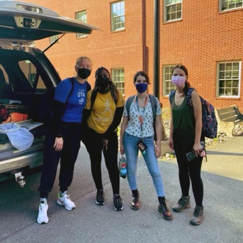 Four masked students stand outside.