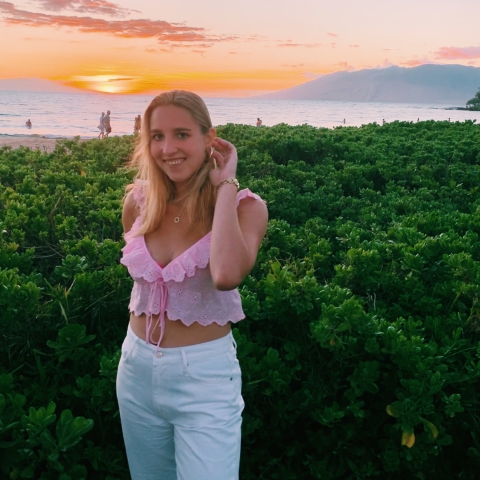 Olivia Scotti '22 stands outside with the sunset behind