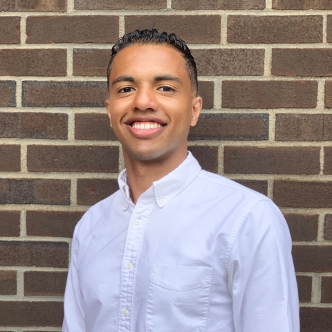 Adem Ahmed &#039;16 stands in front of a brick wall