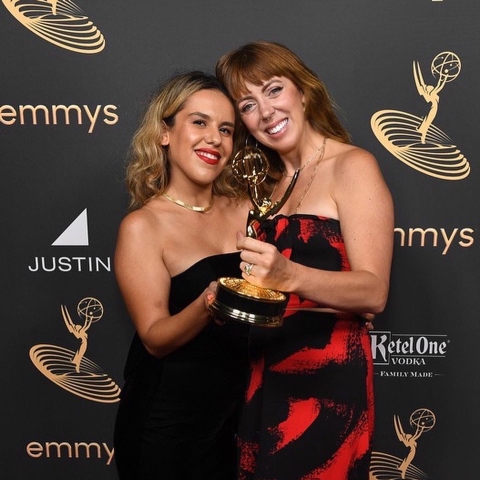 Two women pose with an Emmy award.