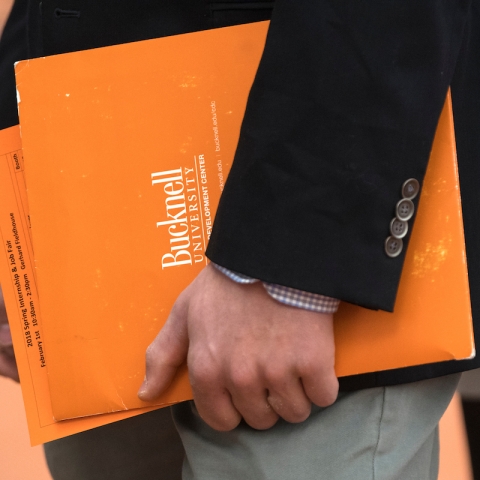 A close up image of a student holding orange folders