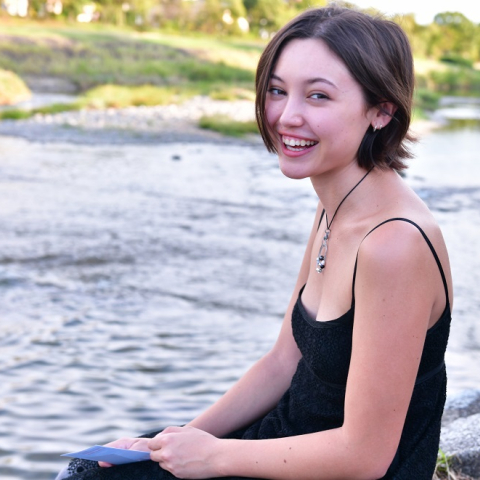 Brooke Corpez sits and smiles with a river behind her.