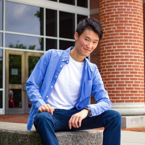 Jaden Lee sitting on a wall outside Academic West