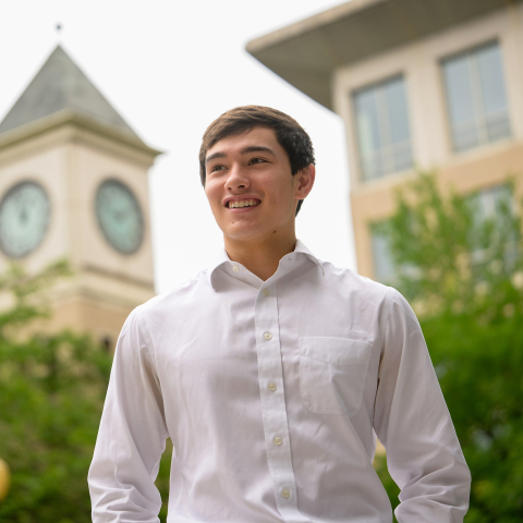 Max Quan wears a white shirt with a clock tower in the background.