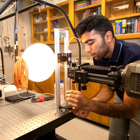 Abdullah Nabi ’23 leans over a workbench in his mechanical engineering lab