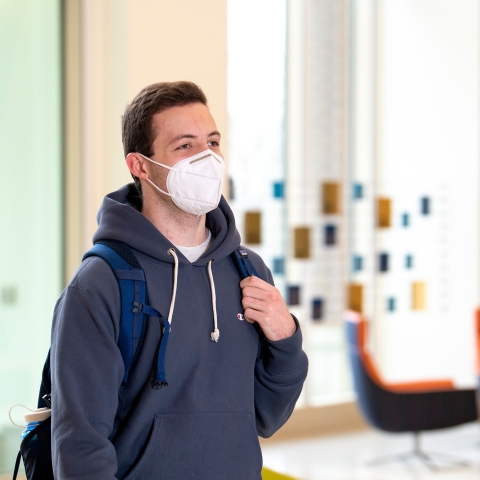 A male student in a KN95 mask walks in Holmes Hall