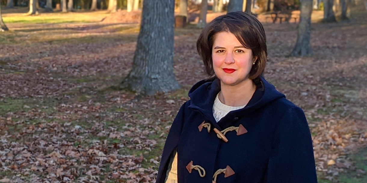 Casey Barber poses before a field of trees and fallen leaves.