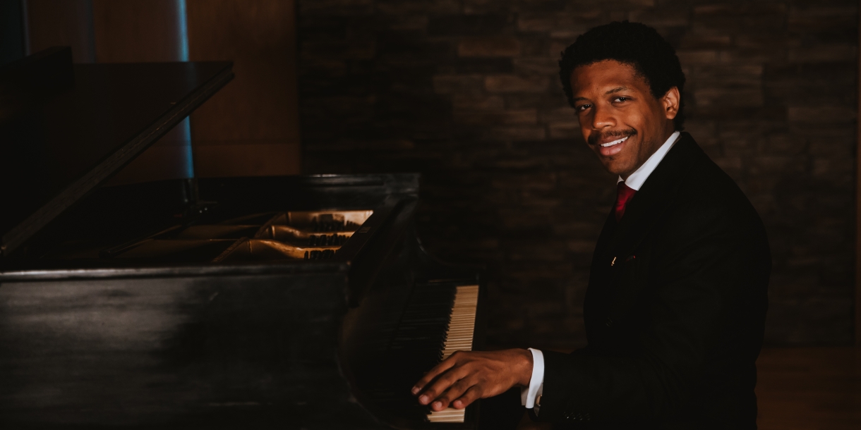 Sean Mason sitting at a piano, smiling at the camera