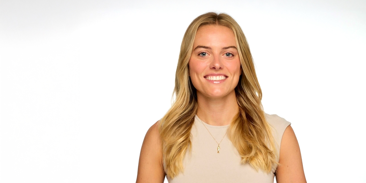 Cricket Treanor '18 smiles while wearing a beige sleeveless top against a white background.