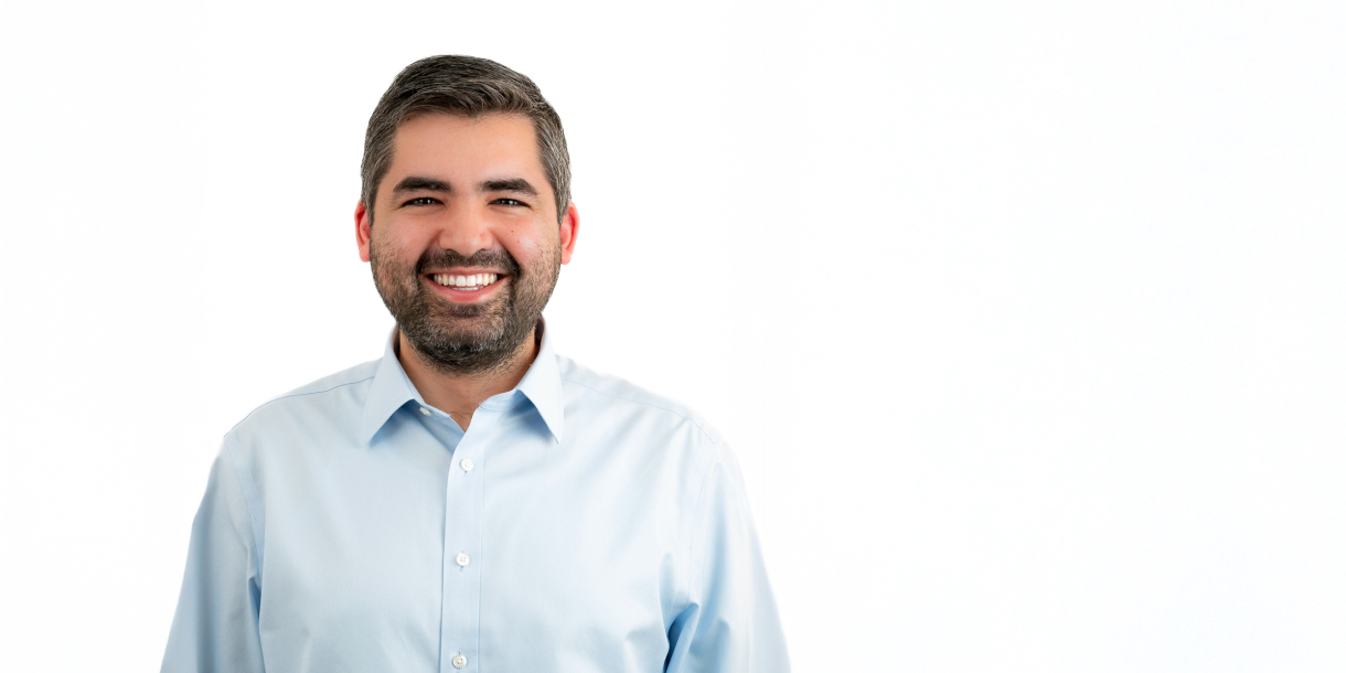 Michel Ajjan wears a white button-down collared shirt and smiles.