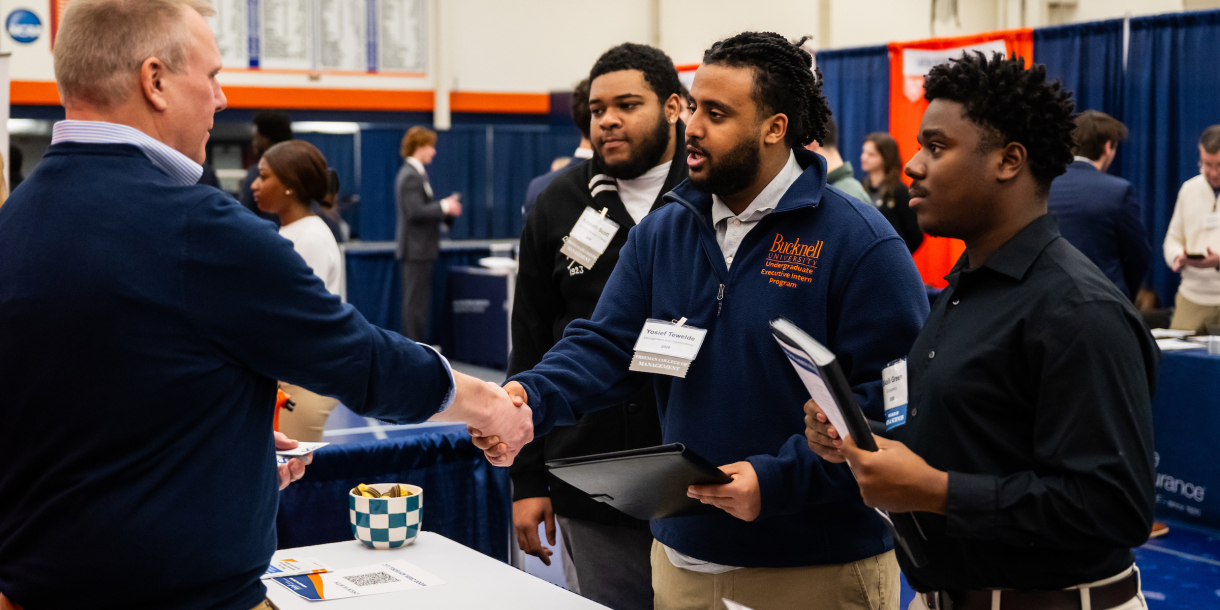 Students at a career fair shake hands with an employer