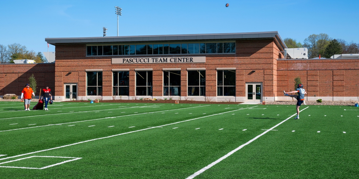 A football kicker practices on the turf in front of the Michael C. Pascucci ’58 Team Center