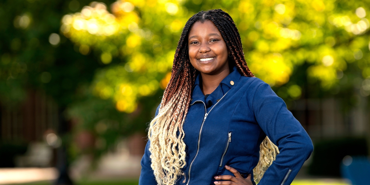 Twity Gitonga poses in a denim shirt and black pants Malesardi Quadrangle.