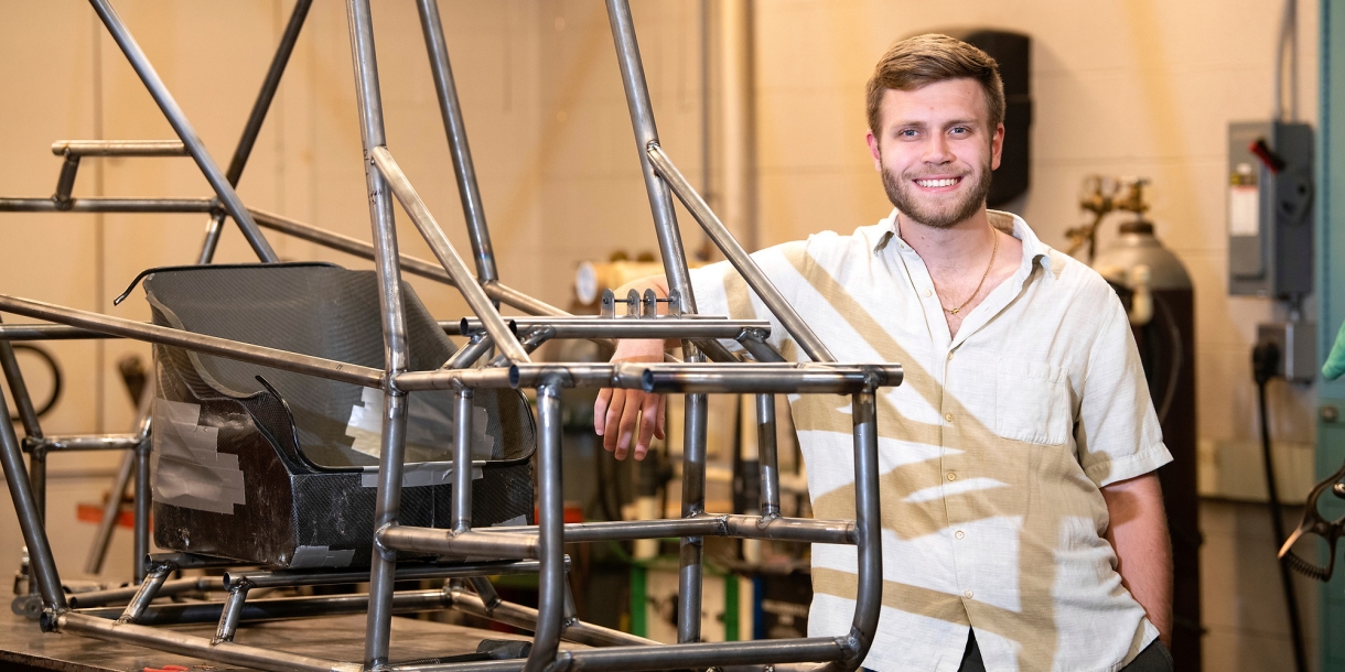 Elliot Thorp &#039;23 stands with a steel frame of a go-kart.