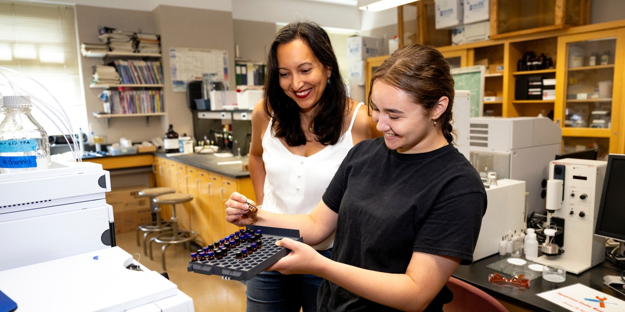 Jacquelyn Awigena-Cook &#039;05 looks on as Brianna Bolorin &#039;24 holds lab equipment in a lab.