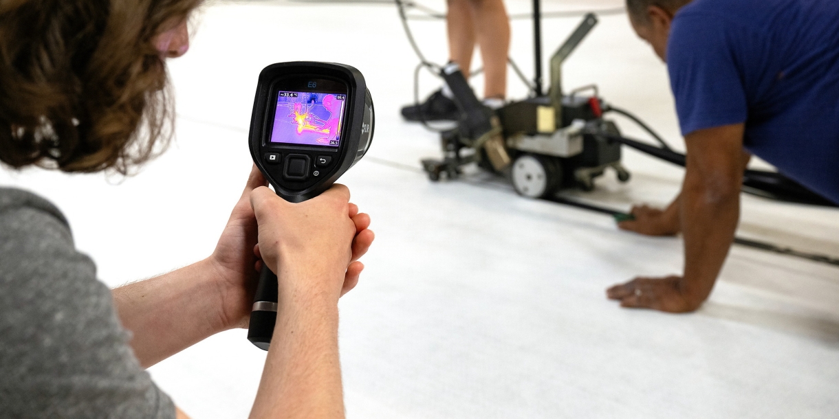 Close up of a student using an infrared camera to collect heat data from a mat welder