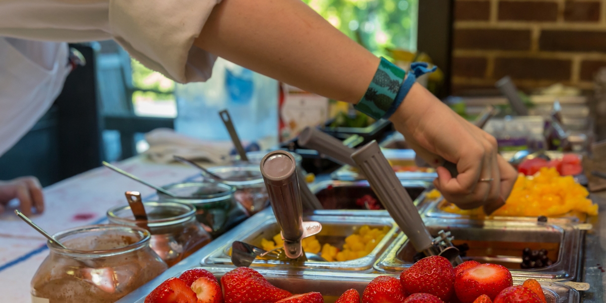 Dining services worker scooping food.