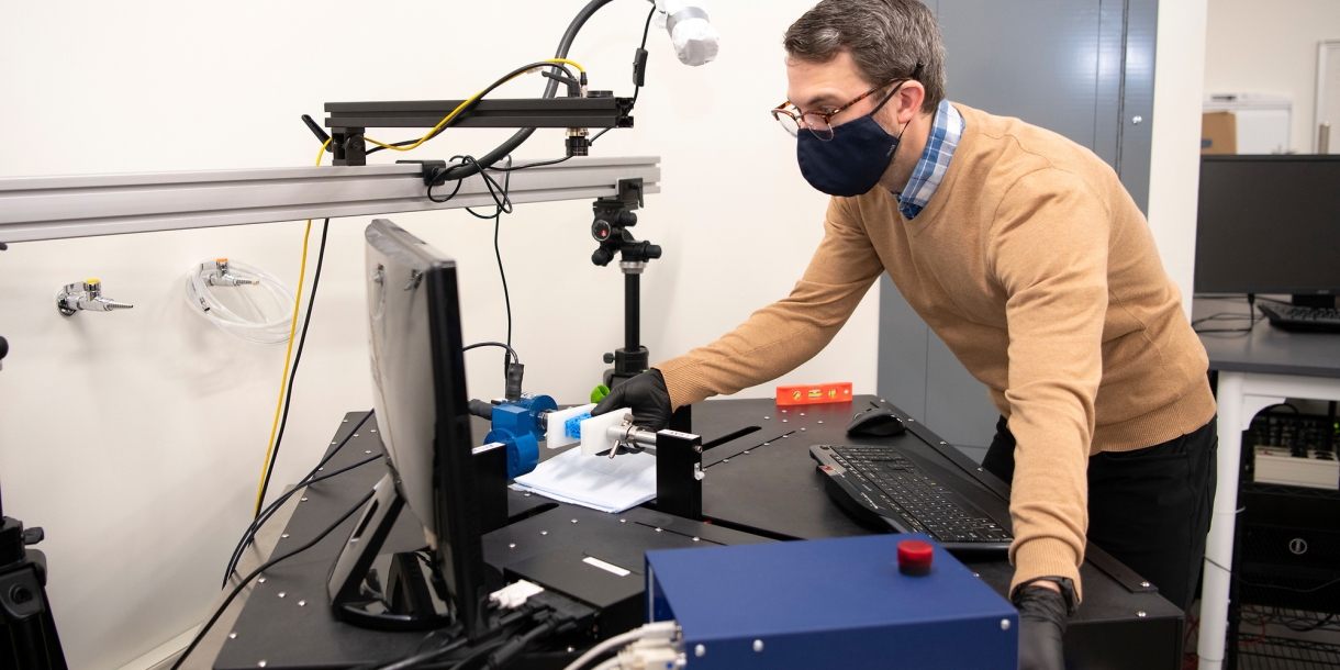 Ben Wheatley leans over a piece of testing equipment next to a computer screen