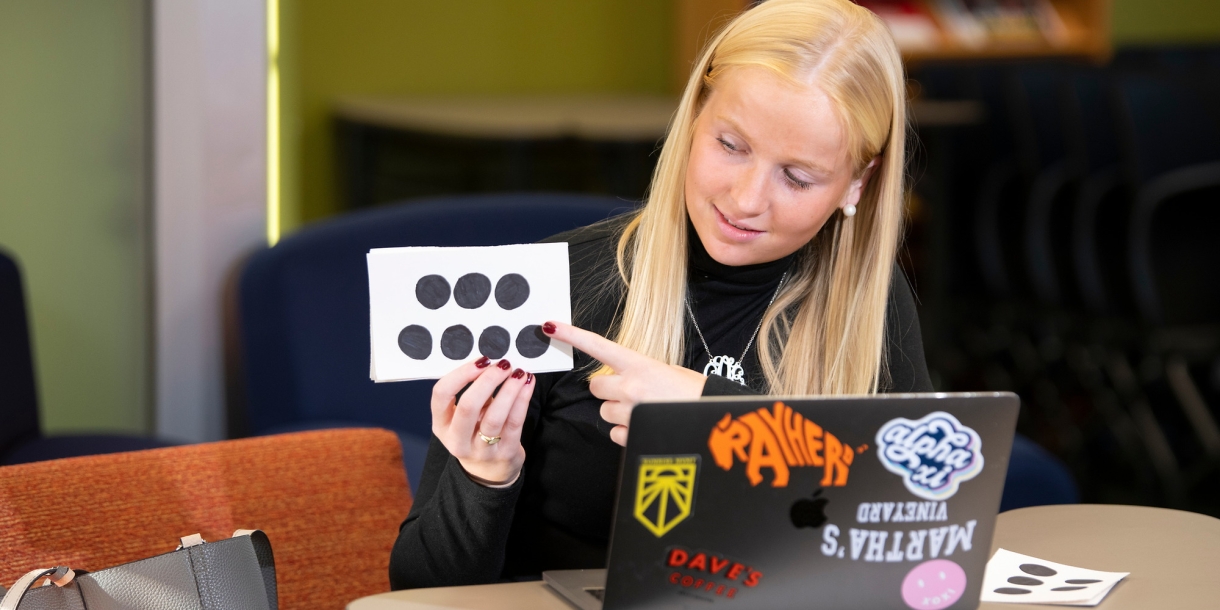 Cara O'Neill points to a flashcard while tutoring elementary school students online