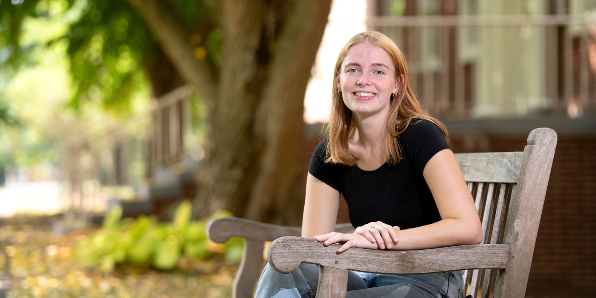 Ella sits on a bench on campus