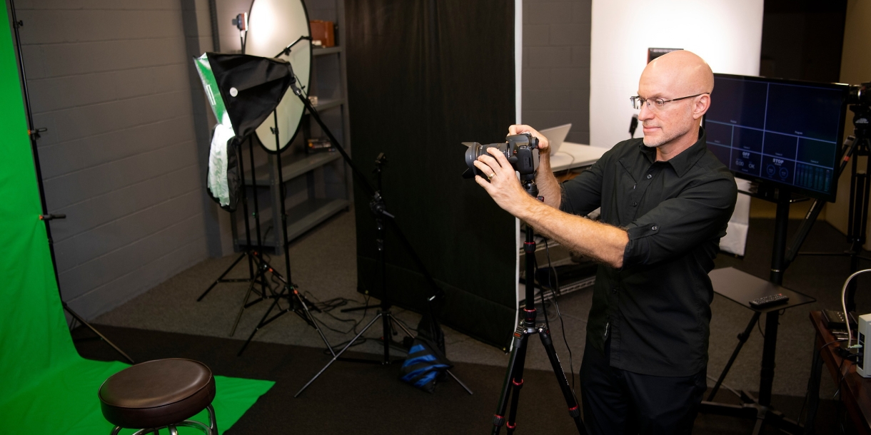 Mark Burke examines a camera while inside a studio.
