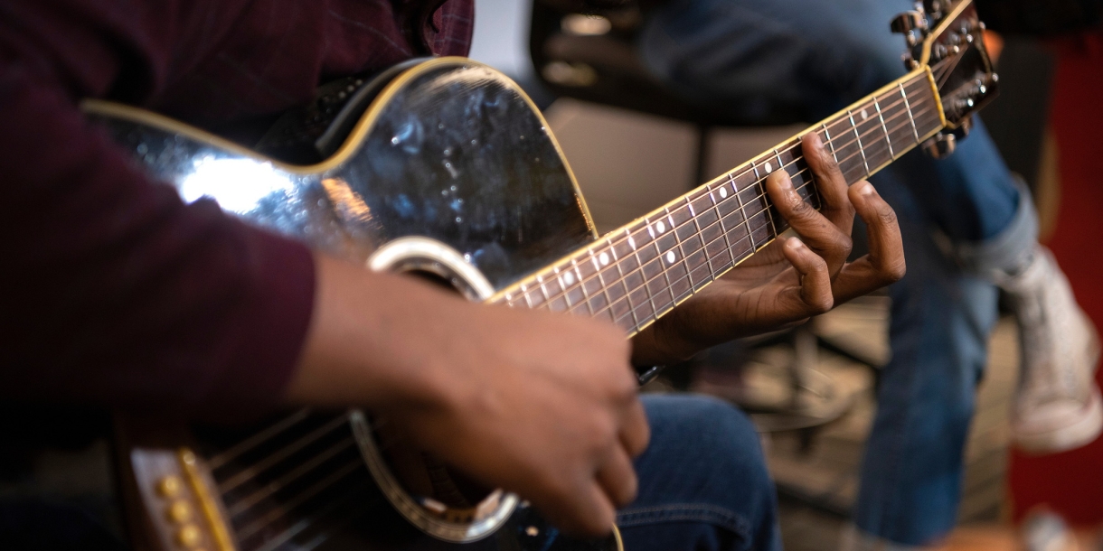 Detail of student playing acoustic guitar