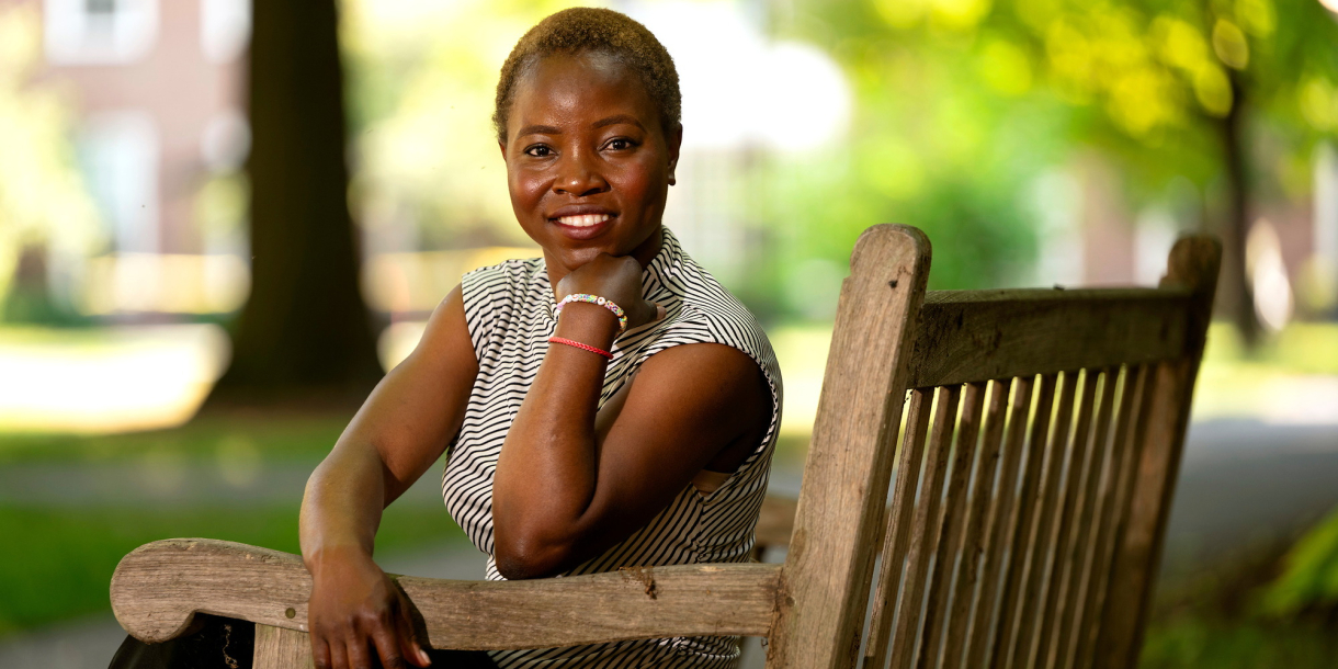 Marie Victoire Alexis sits on a bench on campus and smiles.