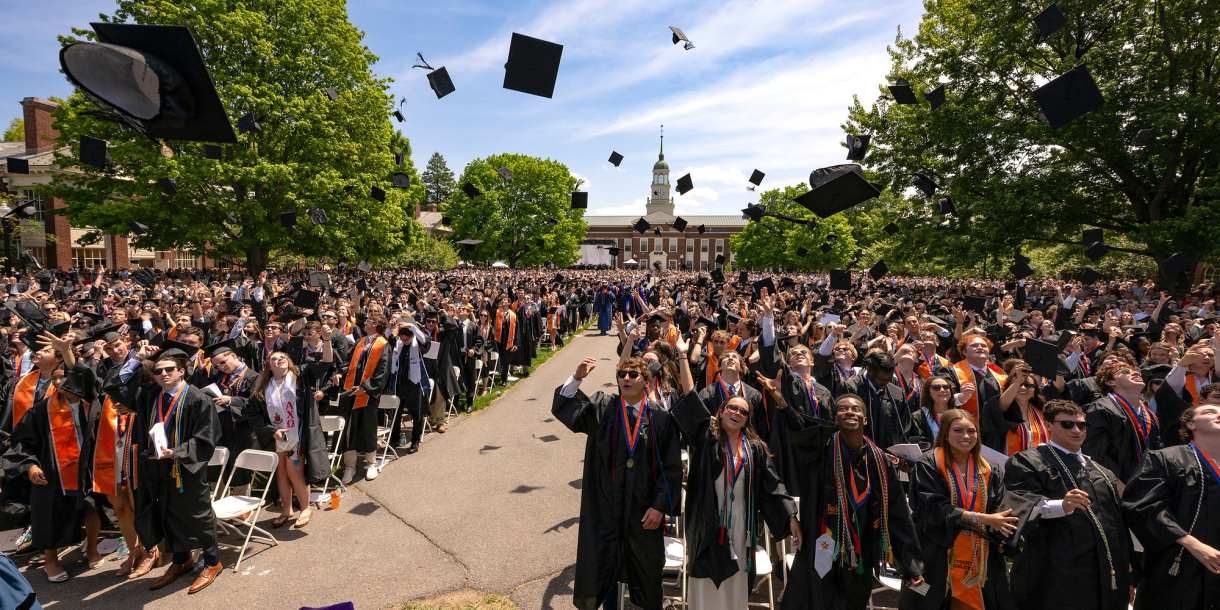Graduates throw their caps into the air while standing outside