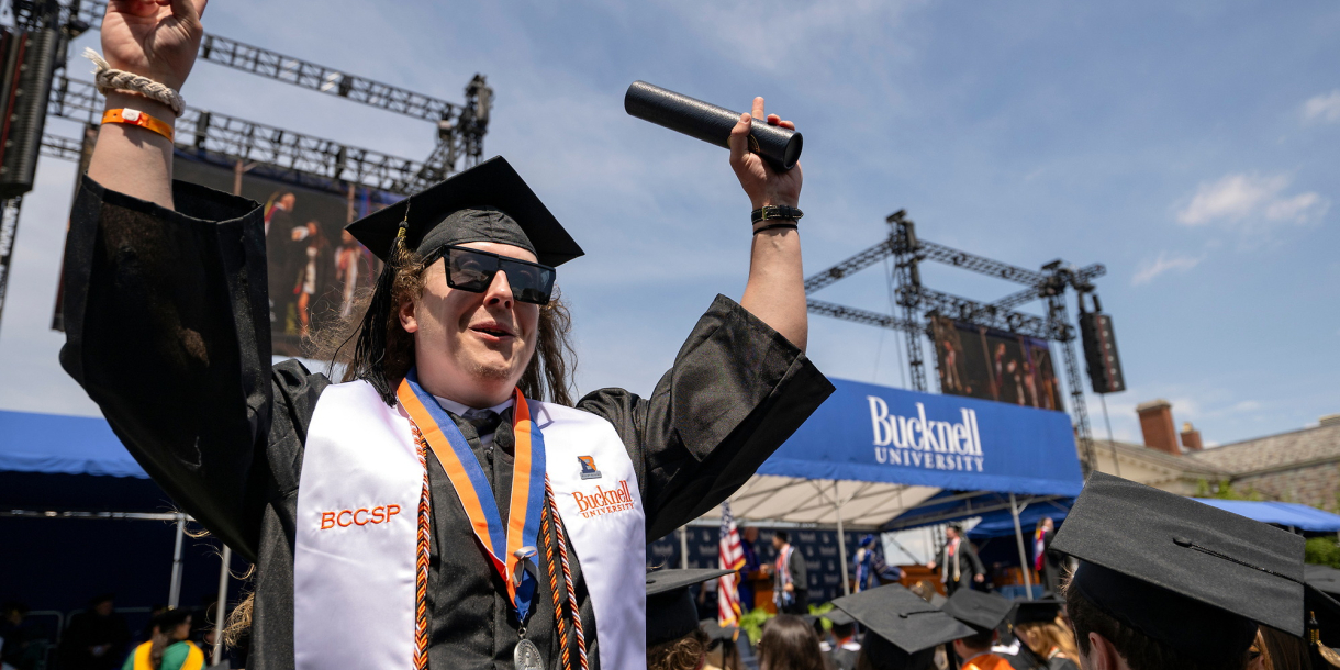 A graduate holds up his degree as he exits the Commencement stage at Bucknell's 2026 Commencement ceremony.