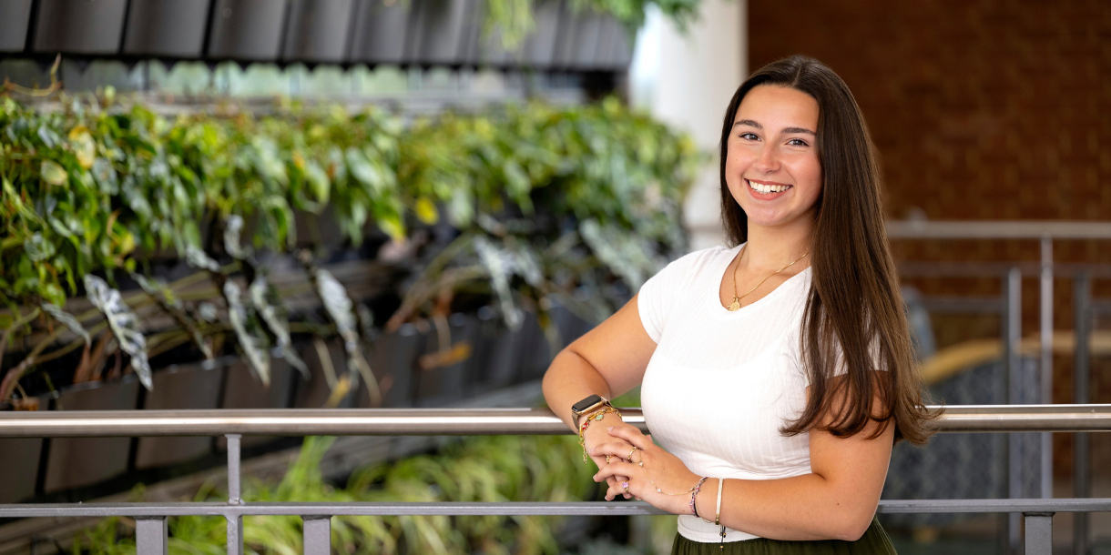 Gianna Sangillo wears a white shirt in front of a green background