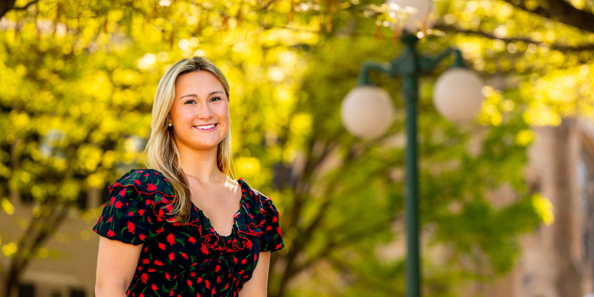 Margo Bigue smiles on campus with bright yellow foliage and a Lewisburg lightpost behind her.