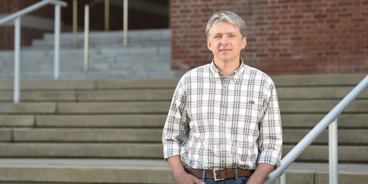 Professor Will Kerber poses on the steps of the Rooke Science Building