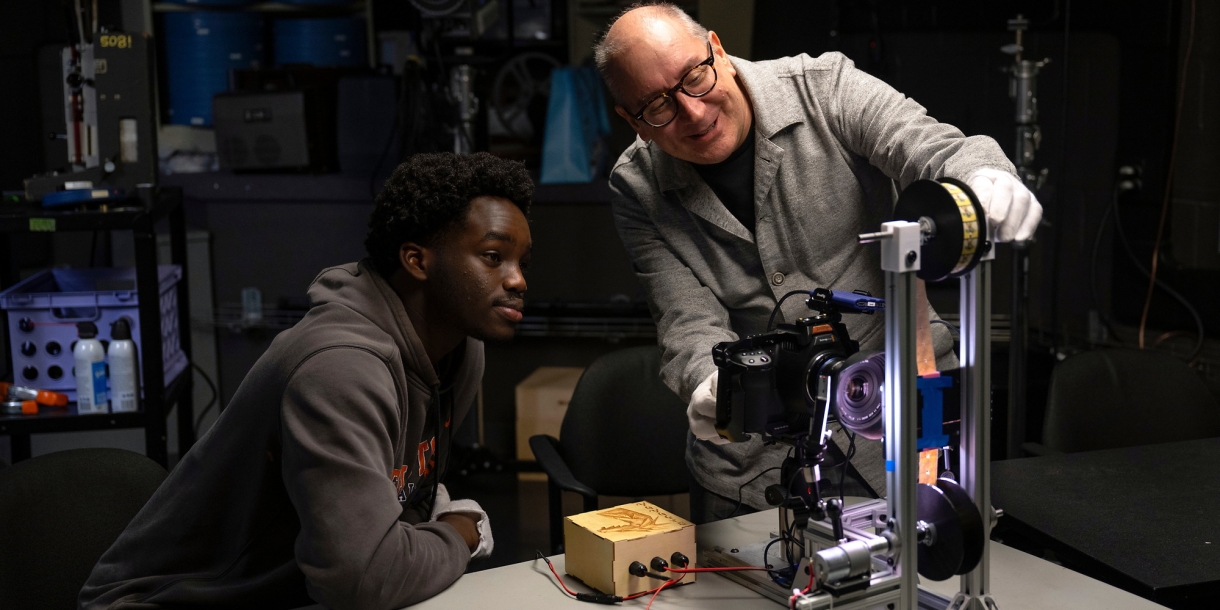 John Ogunwomoju '27 and Professor Eric Faden smile as they work using a film projector