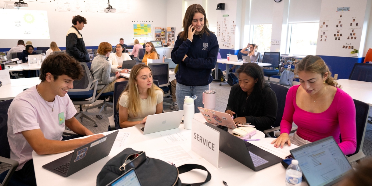 MGMT 101 students work together around a table.