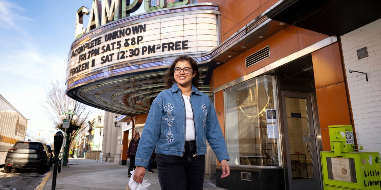 Waina Ali '26 walks down the sidewalk in downtown Lewisburg with the Campus Theatre marquee behind her.