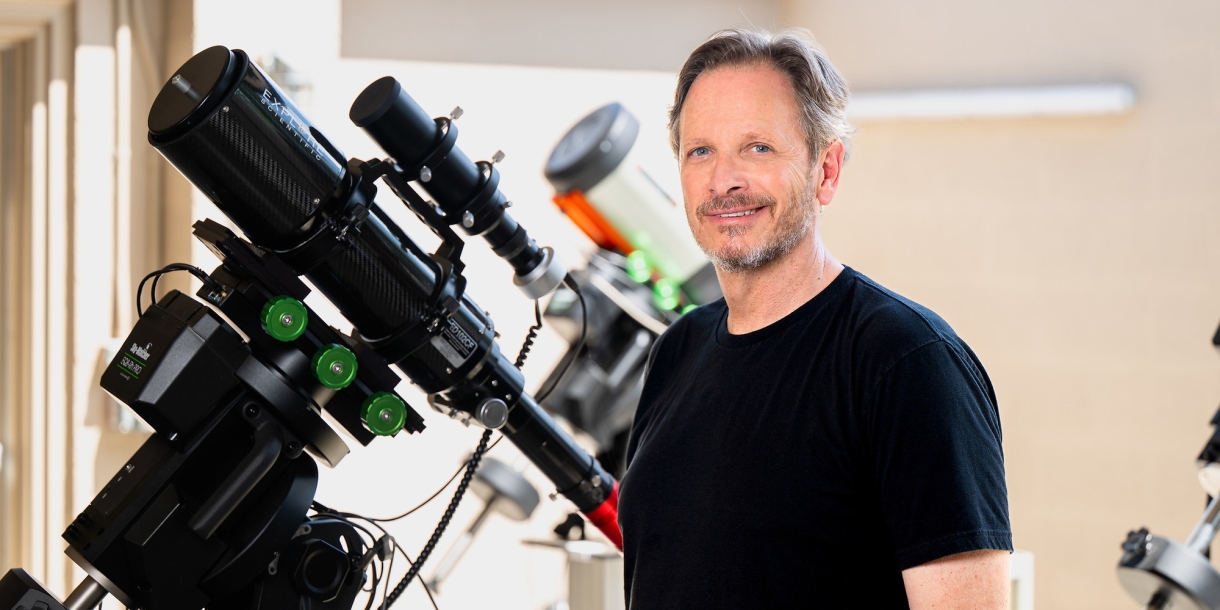 Jack Gallimore stands next to a telescope