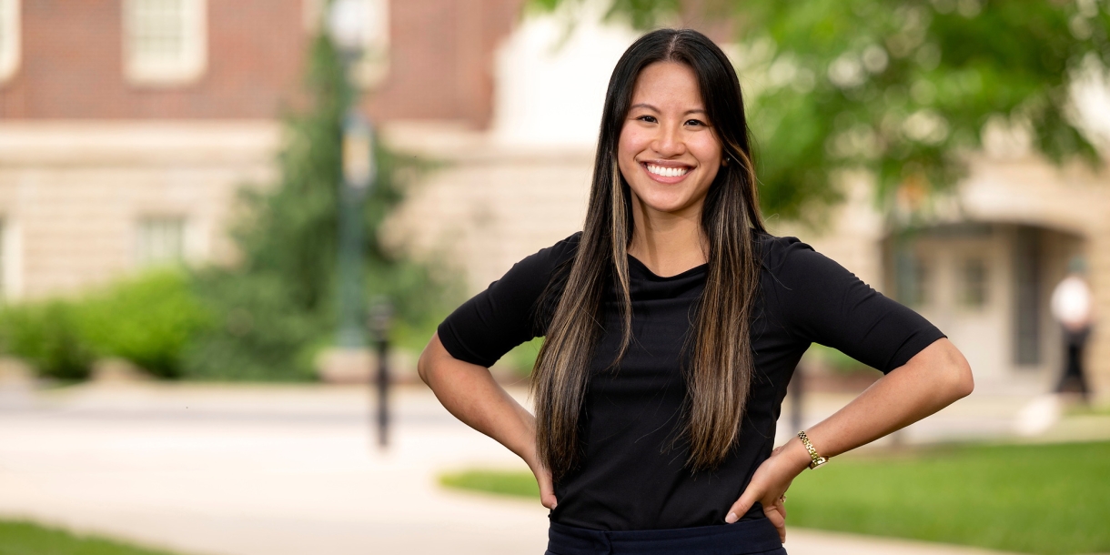 Professor Olivia Boerman stands outside, smiling, with her hands on her hips.