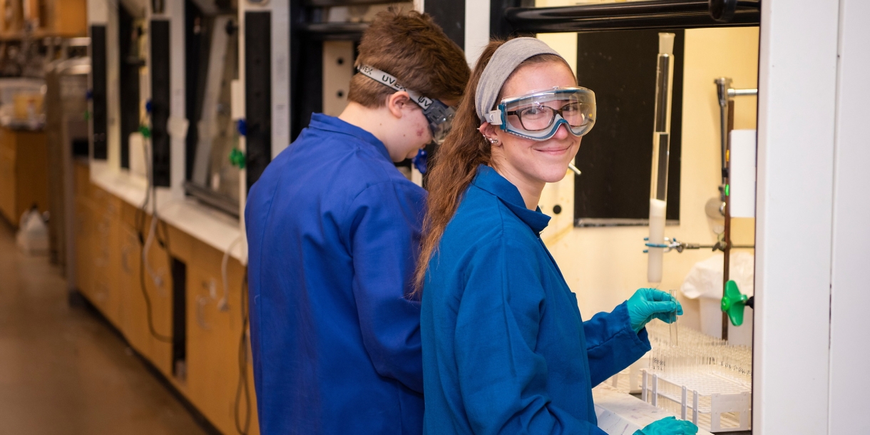 Carly Masonheimer near a hooded workstation in a chemistry lab