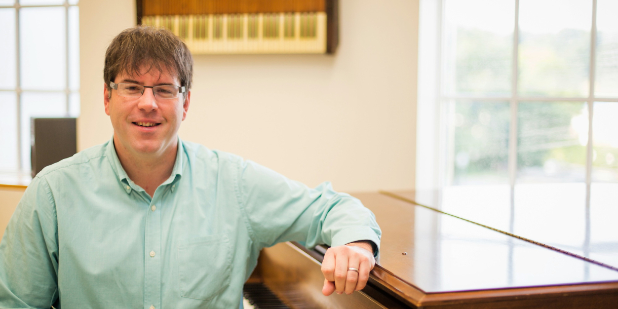 Ryan Malone sits with his elbow propped up on the edge of an organ.