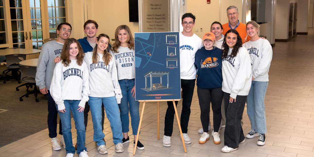 Class of 2022 officers stand with President Bravman alongside an illustration of their class tribute.