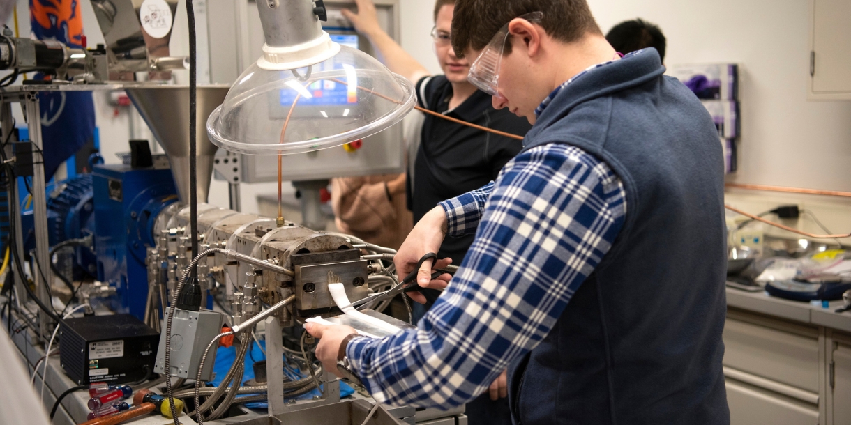 Student carefully cuts material from a machine