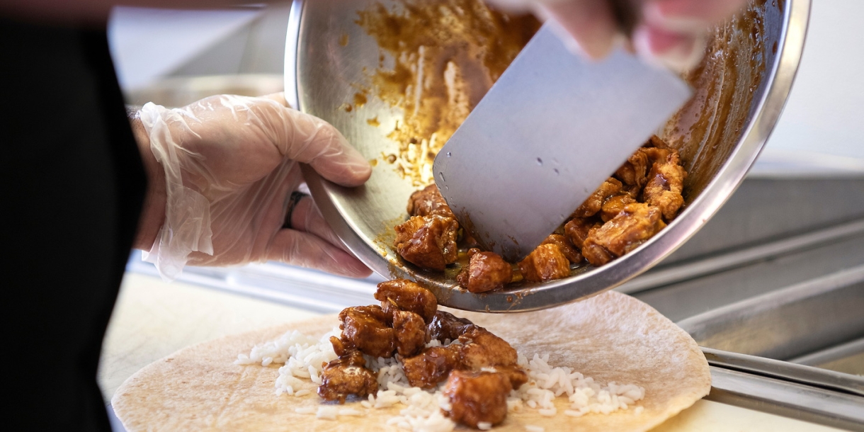 A chef prepares a sauced chicken wrap