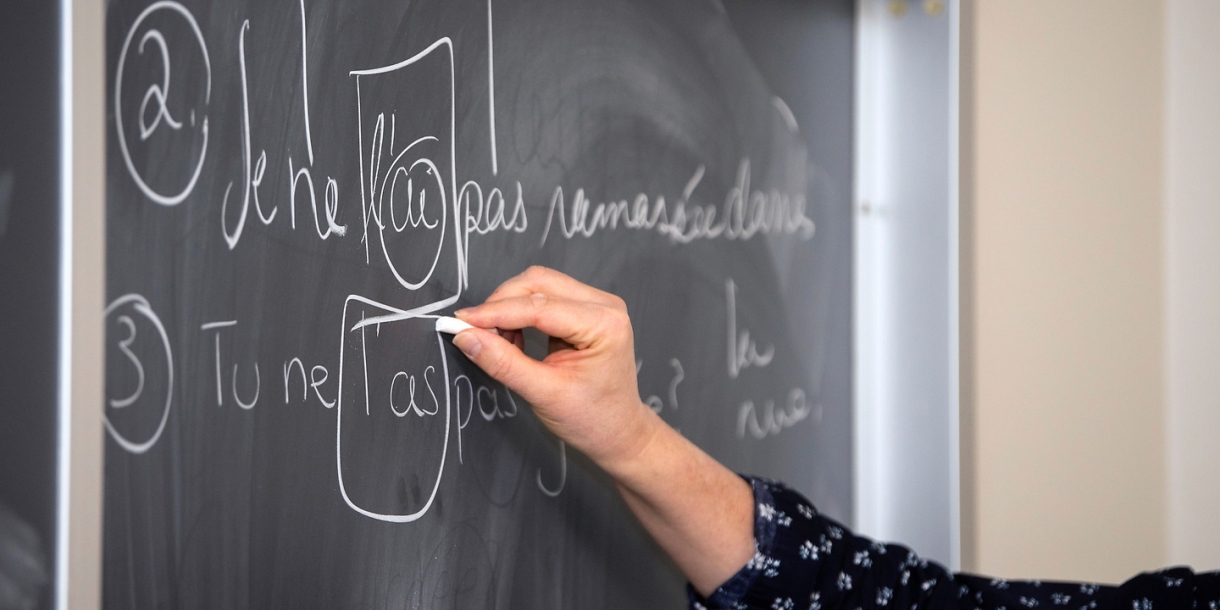 Professor writing French on chalkboard.