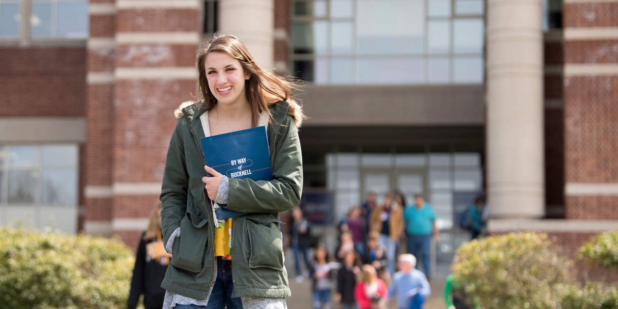 Student exiting a building with papers