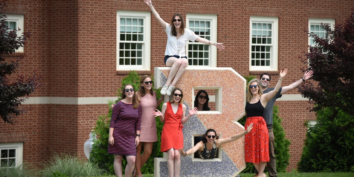 Alumni pose by B statue behind South Campus Apartments