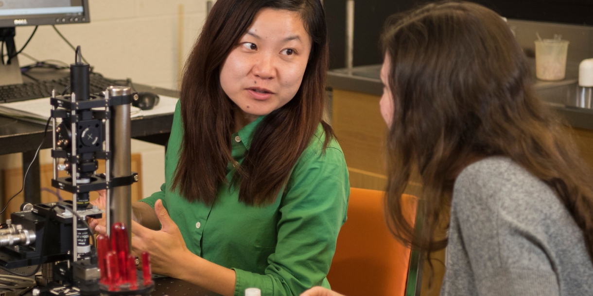 Professor JiaJia Dong talking to a student about an optical tweezer