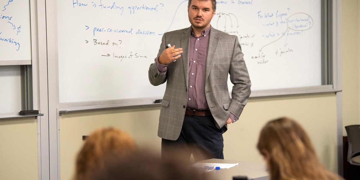 Professor lecturing in front of whiteboard