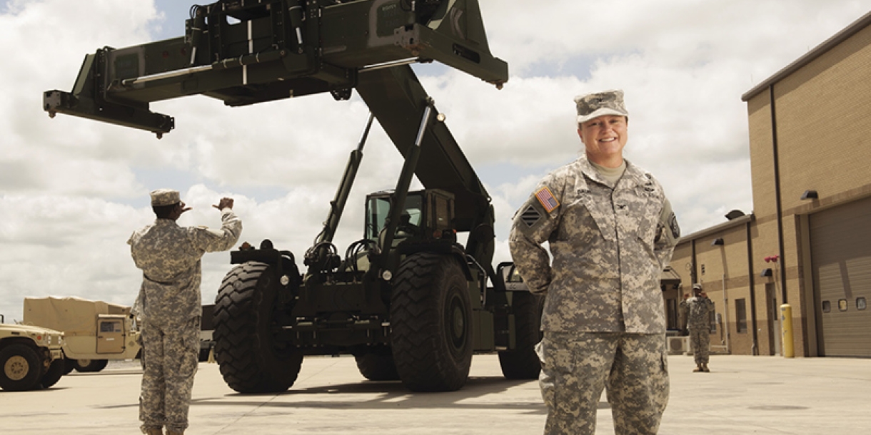 Military woman poses in front of large machinery