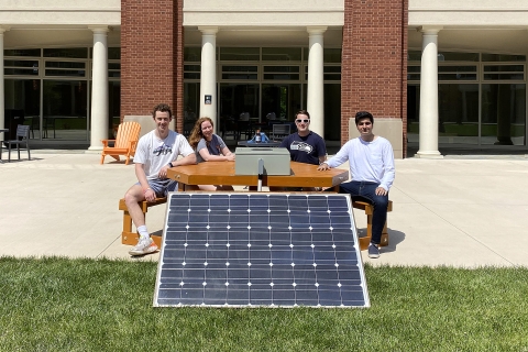 Students sit at a solar bench they helped to build